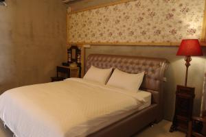 ein Bett mit weißen Laken und einer roten Lampe in der Unterkunft Lost in Memory in Sanxing Township