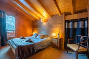 Un dormitorio con una cama y una silla en una habitación. en Chalet Les Alpins, en Le Fernuy