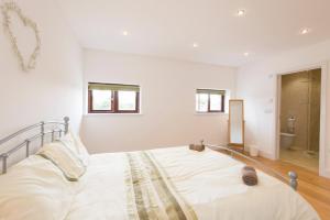 a white bedroom with a bed and a bathroom at Jubilee Cottage - Cwc75016 in Saint Breward