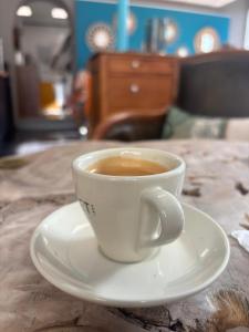 a cup of coffee sitting on a plate on a table at Le Petit Pendentif - cœur de ville cathédrale - rdc in Valence