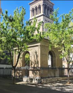 a building with a tower with a fence and trees at Le Petit Pendentif - cœur de ville cathédrale - rdc in Valence