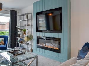 a living room with a fireplace with a tv above it at West Lodge in Sewerby