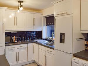 a kitchen with white cabinets and a white refrigerator at West Park House in Penwortham