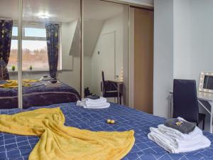 a room with a blue bed with towels and a mirror at West Park House in Penwortham