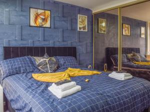 a blue bedroom with a bed with towels on it at West Park House in Penwortham +6 photos