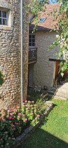 a cat sitting next to a building with pink flowers at Carpe Diem in Saint-Savin-sur-Gartempe