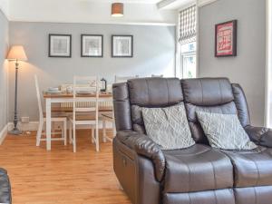 a living room with a leather couch and a table at Woodys in Windermere