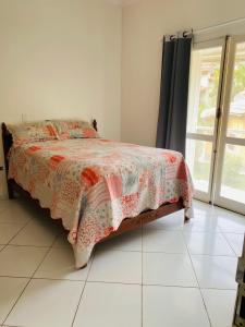 a bedroom with a bed with a flowered blanket on it at Casa Verão Guaratuba - Bertioga in Bertioga +50 photos