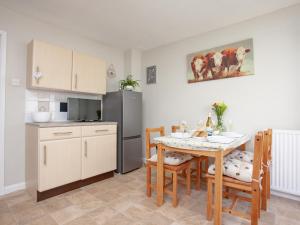 a kitchen and dining room with a table and a refrigerator at Jubilee Cottage in Dawlish