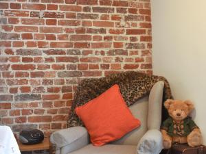 a teddy bear sitting on a couch next to a brick wall at Holme Cottage in Eastry