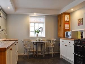 a kitchen with a table and chairs and a window at Holme Cottage in Eastry