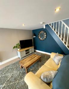 ein Wohnzimmer mit einer Couch und einer Uhr an der Wand in der Unterkunft Sunset Cottage in Hunstanton + 3 Fotos
