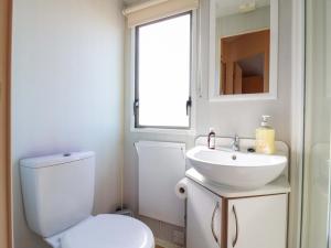 a bathroom with a toilet and a sink and a window at Singh Leite & Luisa Family Caravan in Jaywick Sands +10 photos