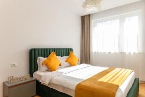 a bedroom with a large bed with yellow pillows at JAD Luxury 3 Rooms Apartments Urban Plaza in Braşov