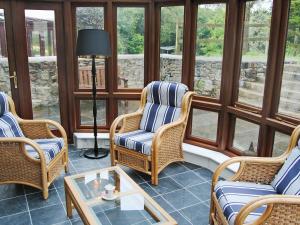een afgeschermde veranda met rieten stoelen en een tafel bij Prideaux Cottage in Luxulyan
