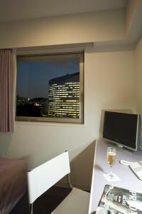 a room with a desk with a computer and a glass of wine at Hotel Mid In Meguro Ekimae in Tokyo