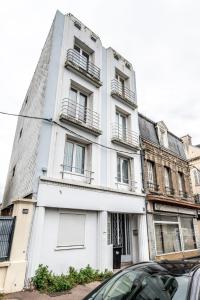 un bâtiment blanc avec des fenêtres et une voiture garée devant dans l'établissement Marine comfort T3 cozy city center WiFi & Netflix, au Havre