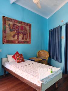 a bedroom with a bed with a painting on the wall at Mayur Guest House in Pushkar