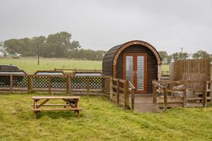 a wooden cabin with a table and benches in a field at Unit 2 - Carrock View Camping Pod in Carlisle +11 photos