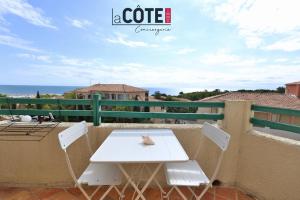 een witte tafel en stoelen op een balkon met uitzicht op de oceaan bij Ciel et mer in Sausset-les-Pins