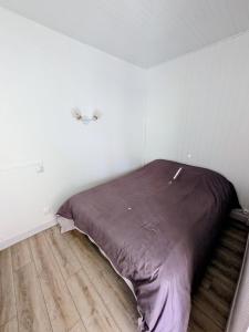 a bed in a white room with a wooden floor at La Cahute des Tamaris in Mimizan-Plage +6 photos