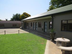 a building with two benches and a grass yard at Villa Strada Guesthouse in Klerksdorp +22 photos