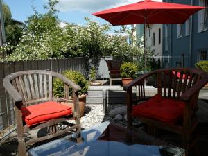 two chairs with red cushions sitting under an umbrella at Bergland Hotel - Adults only in Salzburg