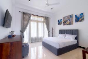 Harohi Hotel and Residence في نيجومبو: غرفة نوم بها سرير وتلفزيون في الغرفة