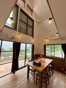 a dining room with a table and some windows at 高井旅コテージ ログハウス - Takaitabi Cottage and LogHouse in Chiji