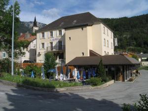 a hotel with chairs and umbrellas in front of a building at Hôtel Restaurant Les Alpins in Saint-Julien-en-Beauchêne