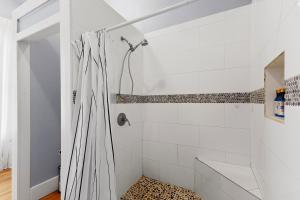 a white bathroom with a shower with a leopard rug at Ellie Marie House LITE in Seguin
