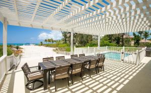 Un patio con mesa y sillas y la playa. en Villa Turkuaz Entire Beach Front Villa, en Long Bay Hills