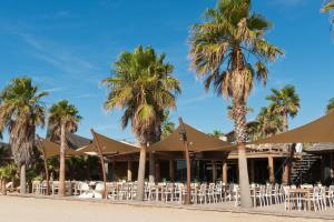 a resort with white chairs and palm trees on the beach at Mobil Homes Vacances in Grimaud