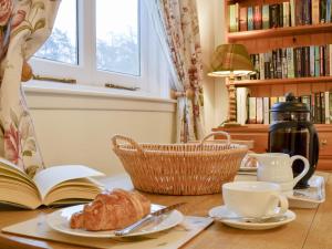 a table with a book and a cup and a croissant at The Coach House-Uk41649 in Blairgowrie