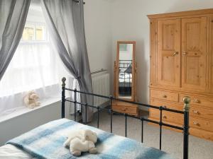 a teddy bear laying on a bed in a bedroom at The White Cottage in Gargrave +16 photos