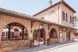 ein altes Backsteingebäude an der Ecke einer Straße in der Unterkunft Le Relais Des Dix Crus - Logis Hôtel B&B in Corcelles-en-Beaujolais