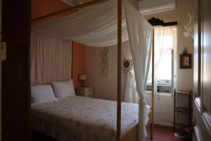ein Schlafzimmer mit Himmelbett und Fenster in der Unterkunft Traditional cottage house in front of the beach in Ríva