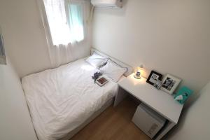 a small bedroom with a white bed and a desk at Stay107 in Seoul