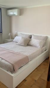 a white bed with white pillows and a white wall at Suite Incanto lago di Garda in Torri del Benaco