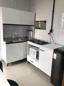 a white kitchen with a stove and a microwave at Kitnet Nova e Aconchegante in Cachoeira do Sul