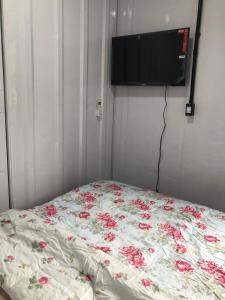 a bed with red flowers on it in a room at Kitnet Nova e Aconchegante in Cachoeira do Sul