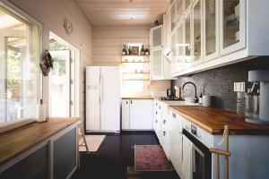 a kitchen with white cabinets and a white refrigerator at Stay North - Västerskog in Västerskog