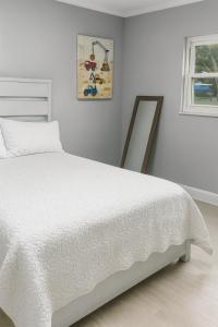 a white bedroom with a bed and a mirror at Relax & Explore Gulf Coast Modern Stay in Spring Hill