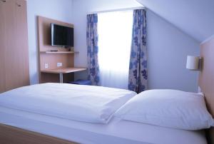 a bedroom with a bed and a window with a television at Hotel Bahnhof Jestetten in Jestetten