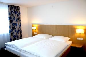 ein Schlafzimmer mit einem großen weißen Bett mit zwei Kissen in der Unterkunft Hotel Bahnhof Jestetten in Jestetten