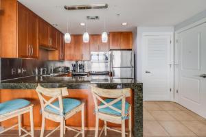 a kitchen with wooden cabinets and blue chairs at a counter at The Driftwood Oasis in Biloxi