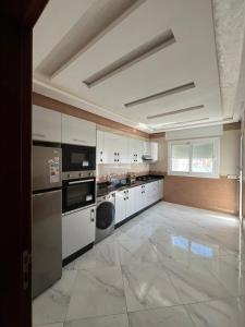 a large kitchen with white cabinets and appliances at Luxe app 2 chambres in Tangier