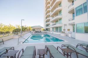 a swimming pool with chairs and a building at The Driftwood Oasis in Biloxi
