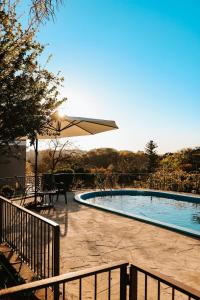 een zwembad met een parasol en een tafel en stoelen bij Alma do Vale Hospedaria in Bento Gonçalves