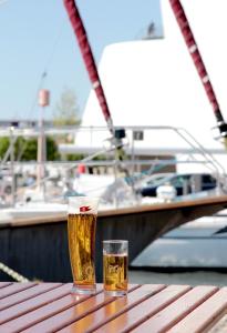 two glasses of beer sitting on a wooden table with a boat at Pension Klabautermann in Stralsund